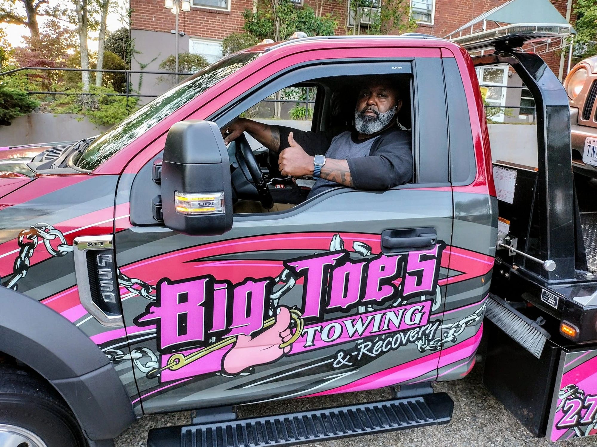 Big Toe giving a thumbs up from his pink Big Toe's Towing & Recovery truck